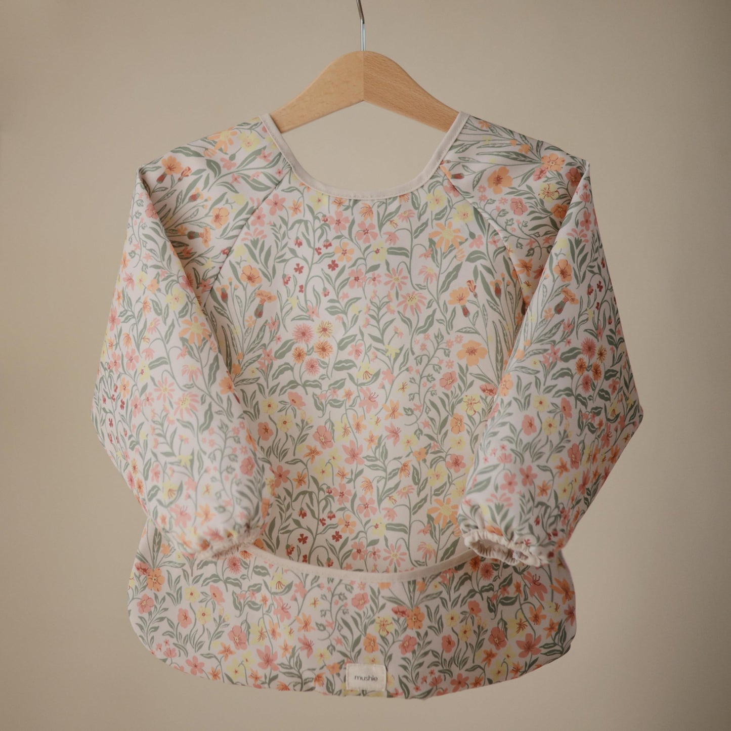 mushie Long Sleeve Baby Bib | Water Resistant Adjustable Fit for Ages 6-24 Months (Pastel Blooms)