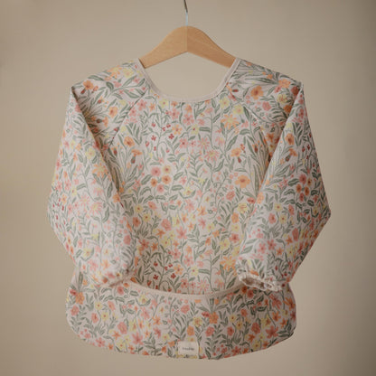 mushie Long Sleeve Baby Bib | Water Resistant Adjustable Fit for Ages 6-24 Months (Pastel Blooms)